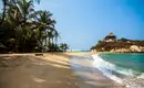 Ein idyllischer Sandstrand im Tayrona-Nationalpark mit türkisem Wasser und Palmen.