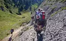 Gruppe von Wanderern auf schmalem Bergpfad in alpiner Landschaft.