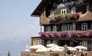 Charmanter Alpengasthof mit Blumenbalkonen in alpiner Landschaft.