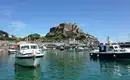 Boote im Hafen vor historischem Gebäude auf Jersey, sonniges Wetter.