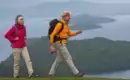 Zwei Personen wandern mit Rucksäcken am Loch Lomond in Schottland.