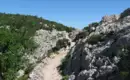 Felsenpfad mit Wanderern und grünem Gebüsch in Sardinien