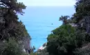 Blick auf das türkisblaue Meer durch Bäume und Felsen in Sardinien.