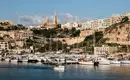 Blick auf den Hafen von Gozo mit Booten und Stadt im Hintergrund.