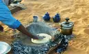 Traditionelles Brotbacken im Wüstensand neben Teekannen