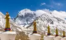 Der schneebedeckte Mount Kailash in Tibet mit Chörten im Vordergrund, blauer Himmel.