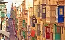 Bunte maltesische Balkone entlang einer sonnigen Straße in Valletta, Malta.