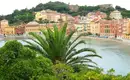 Panoramablick auf ein buntes Küstendorf in der Cinque Terre, umgeben von grüner Vegetation und Meer.