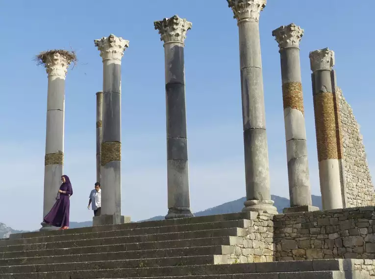 Antike Säulen in Volubilis mit Besuchern im Vordergrund