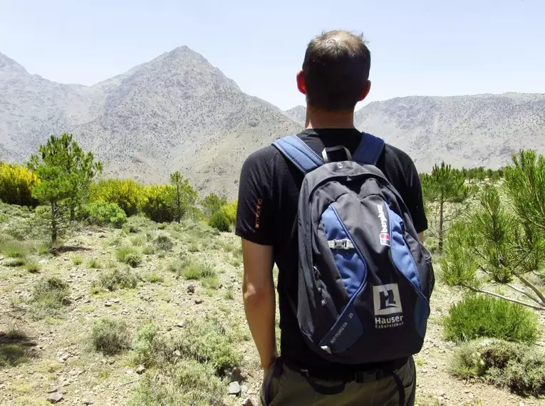 Wanderer mit Rucksack blickt auf Berge im Hohen Atlas, Marokko.