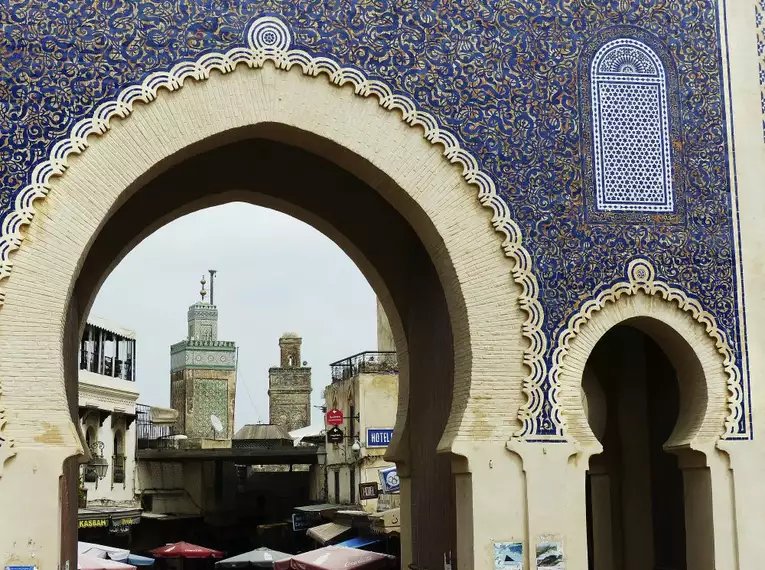 Verziertes Stadttor mit Mosaiken in Fès, dahinter Altstadtansicht.