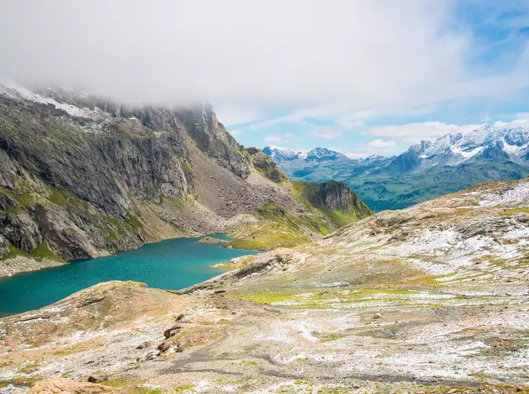 Landschaft in den Schweizer Alpen mit See und Bergen im Hintergrund.