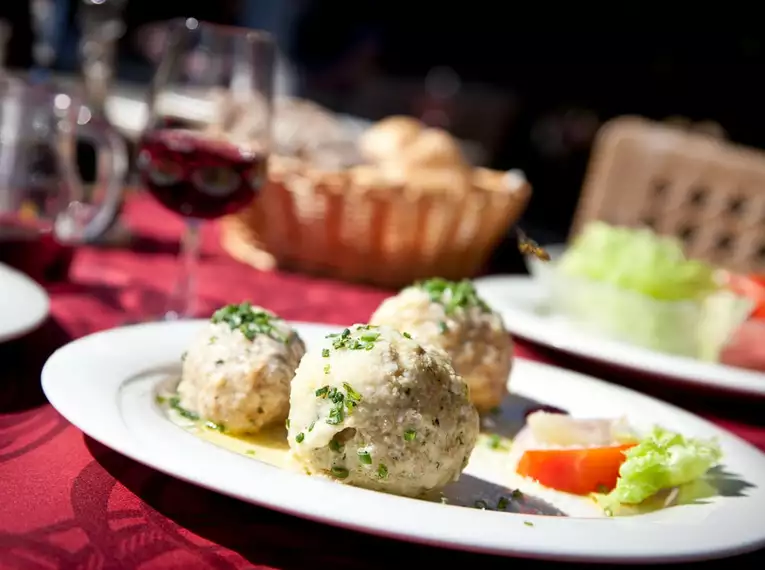 Drei Knödel mit Soße und Salat auf einem Tisch serviert.