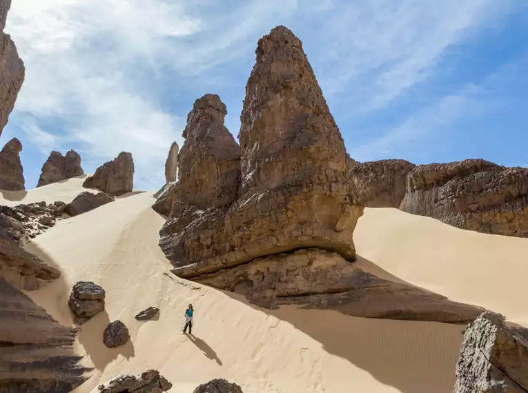 Eine Person wandert durch sandige Felsformationen in Algerien.