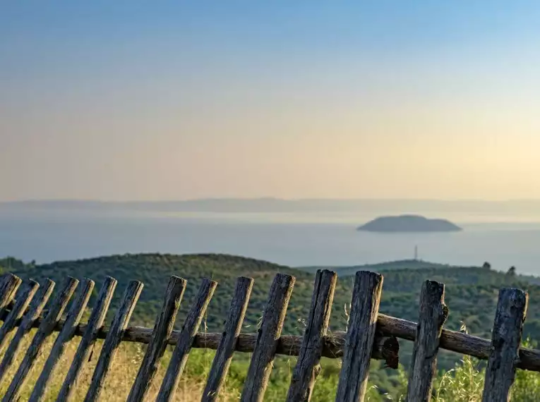 Holzzaun mit Blick auf Hügel und das Meer in Chalkidiki.