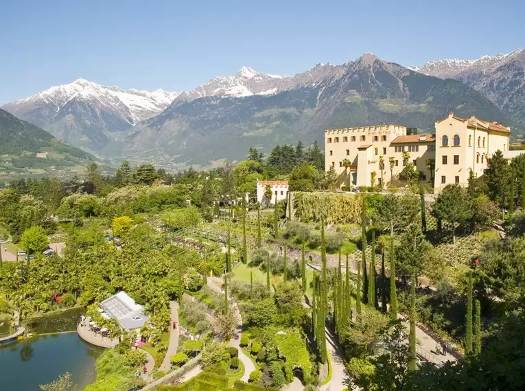 Landschaft der Südtiroler Alpen mit Schloss und Garten bei Meran im Vordergrund.