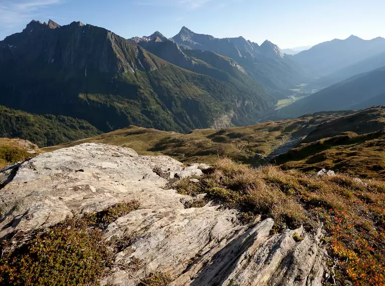 Alpine Landschaft mit beeindruckenden Bergketten und Tälern bei Sonnenschein.