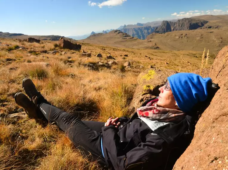 Person entspannt auf einem Felsen in der Berglandschaft der Drakensberge mit weitem Ausblick.