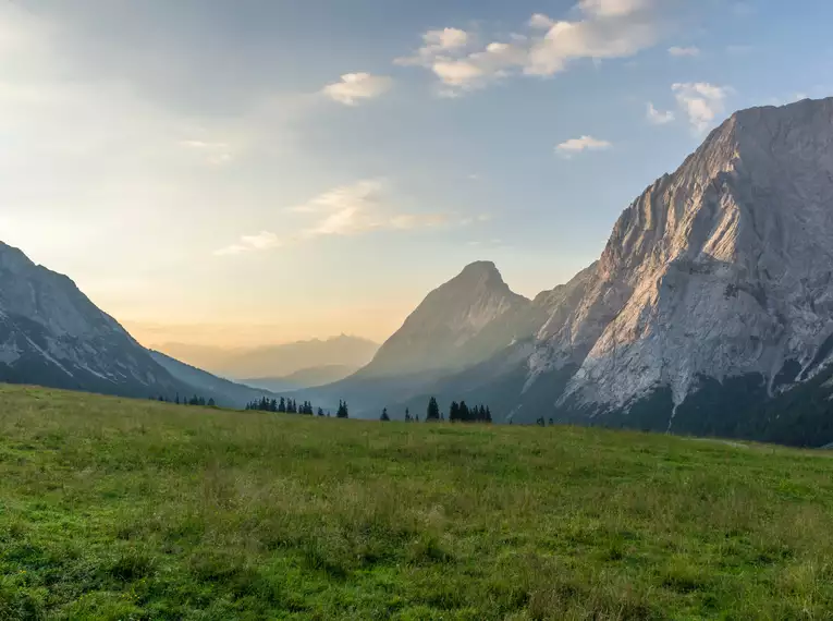 Grüne Almwiese und Berge bei Sonnenuntergang in den Alpen