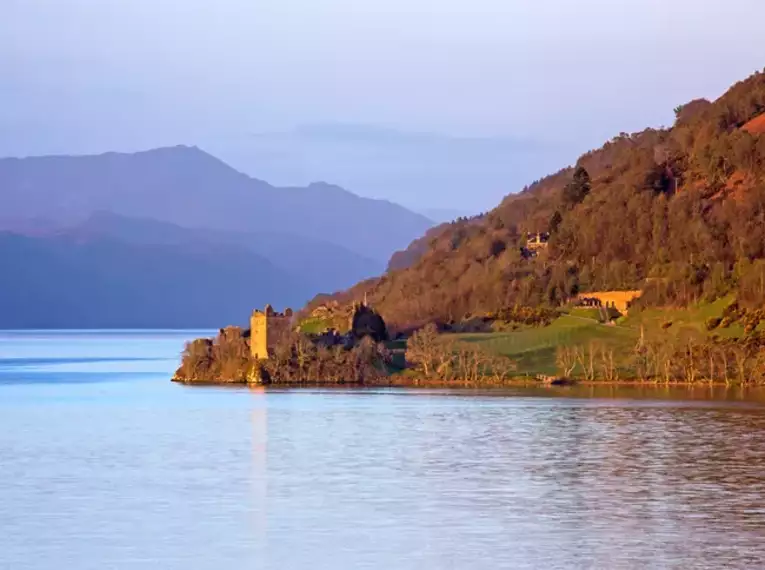 Blick auf Loch Ness mit ruhigem Wasser und weitläufiger Landschaft in Schottland.