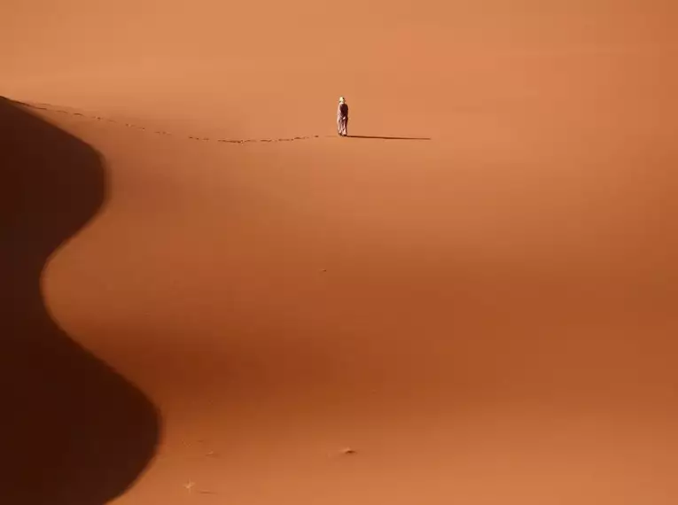 Einzelne Person auf einer Sanddüne in der Sahara bei Sonnenuntergang.