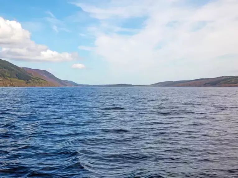 Blick auf Loch Ness mit ruhigem Wasser und weitläufiger Landschaft in Schottland.