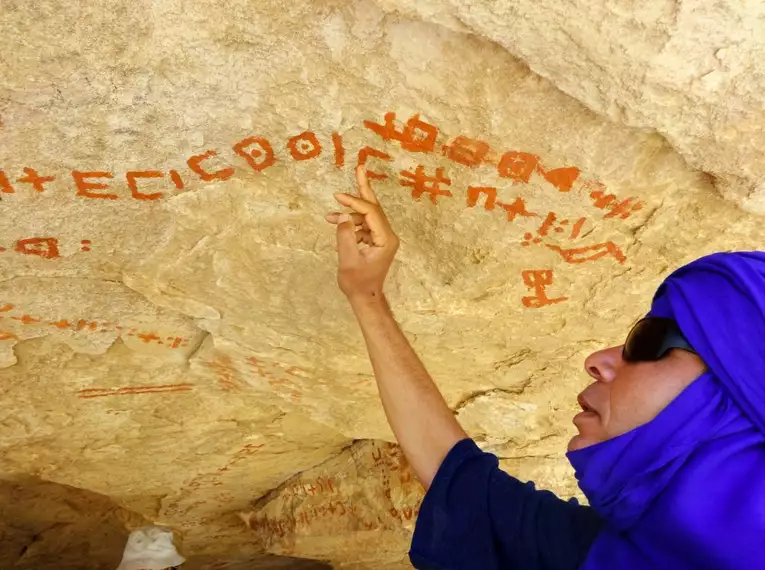 Ein Reiseführer zeigt prähistorische Felsmalereien in der Sahara.