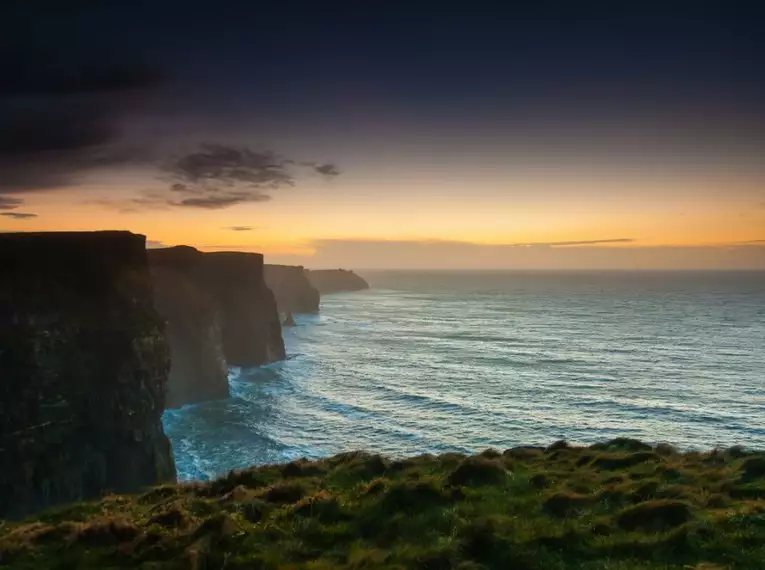 Steilküste in Irland bei Sonnenuntergang mit Meerblick und dramatischem Himmel.