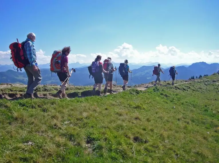 Gruppe von Wanderern im Naturpark Nagelfluhkette mit Blick auf Berge und blauen Himmel.