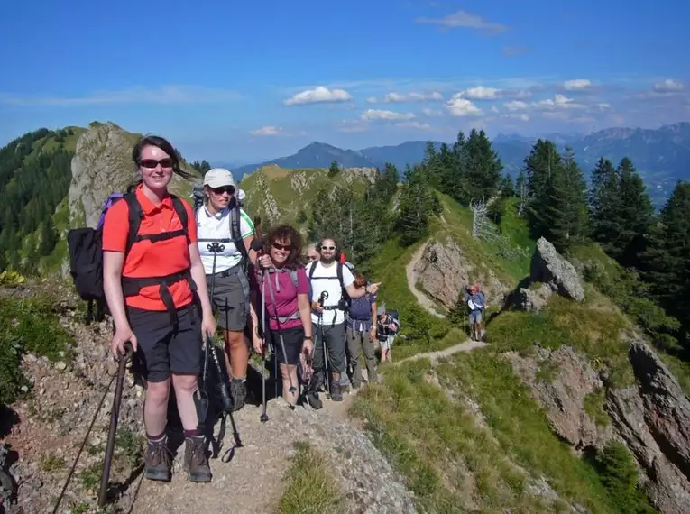 Gruppe von Wanderern auf einem Gebirgspfad im Naturpark Nagelfluhkette mit Alpenpanorama.