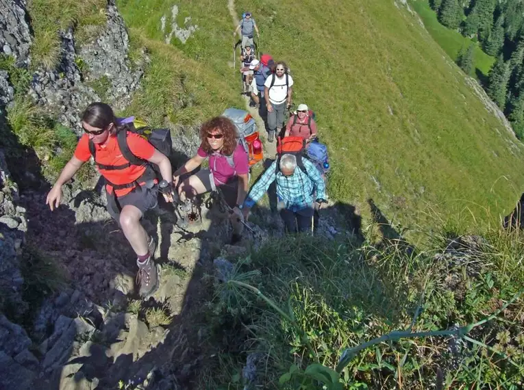 Eine Gruppe von Wanderern auf einem steinigen Pfad im Naturpark Nagelfluhkette.