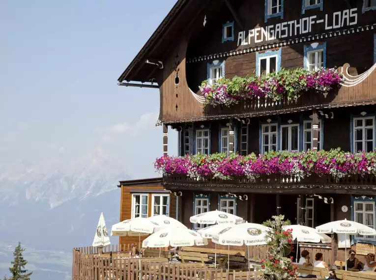 Charmanter Alpengasthof mit Blumenbalkonen in alpiner Landschaft.