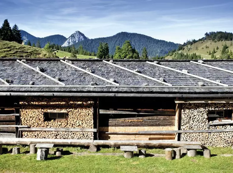 Almhütte vor Bergkulisse in den Alpen bei Sonnenschein