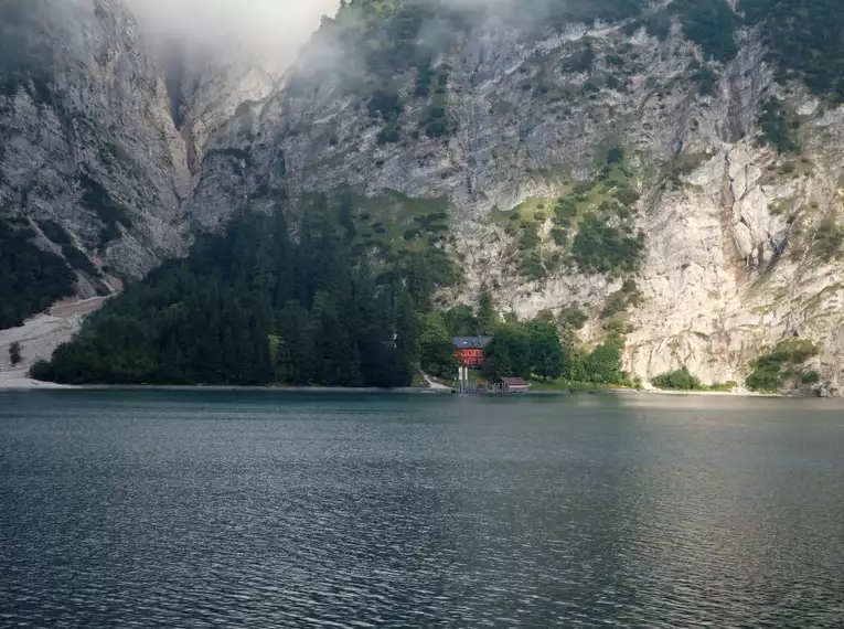 Malerischer Bergsee umgeben von Felsen und Wald im Nebel