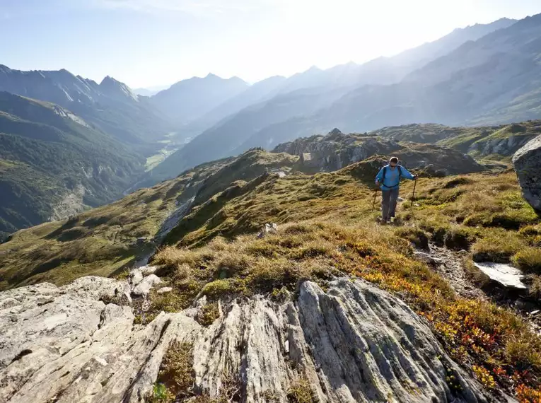 Ein Wanderer in den Alpen mit atemberaubender Bergkulisse und Sonnenschein.