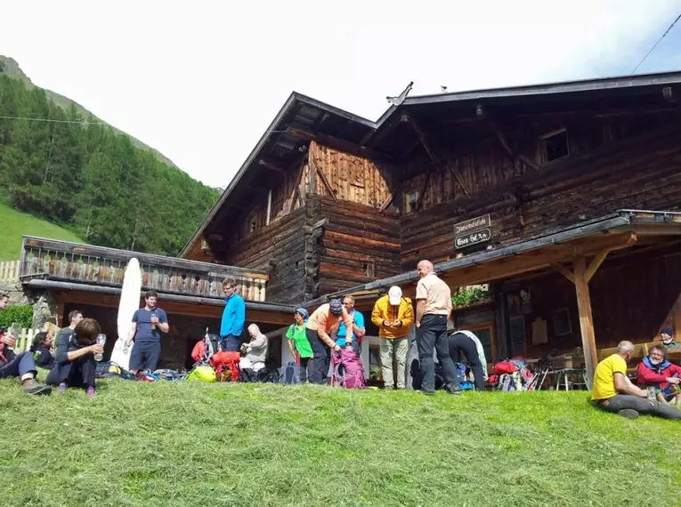 Wanderer genießen eine Pause vor einer traditionellen Alpenhütte in den Bergen.