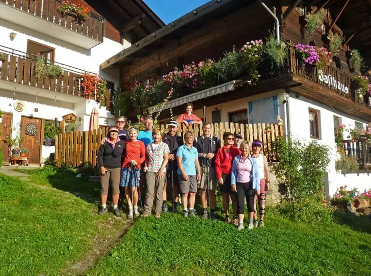 Wandergruppe vor einem traditionellen Alpenhaus mit Holzfassade und Blumen