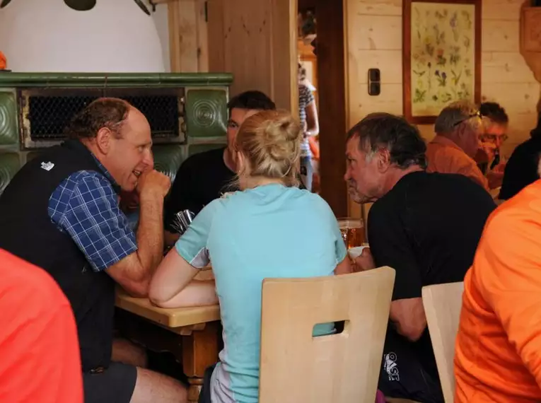 Gäste sitzen in einer gemütlichen Berghütte am Tisch und unterhalten sich.