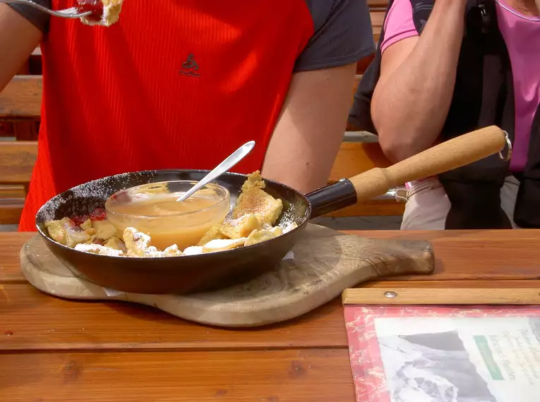 Ein Teller mit Kaiserschmarrn und Apfelmus auf einem Holztisch in den Alpen.