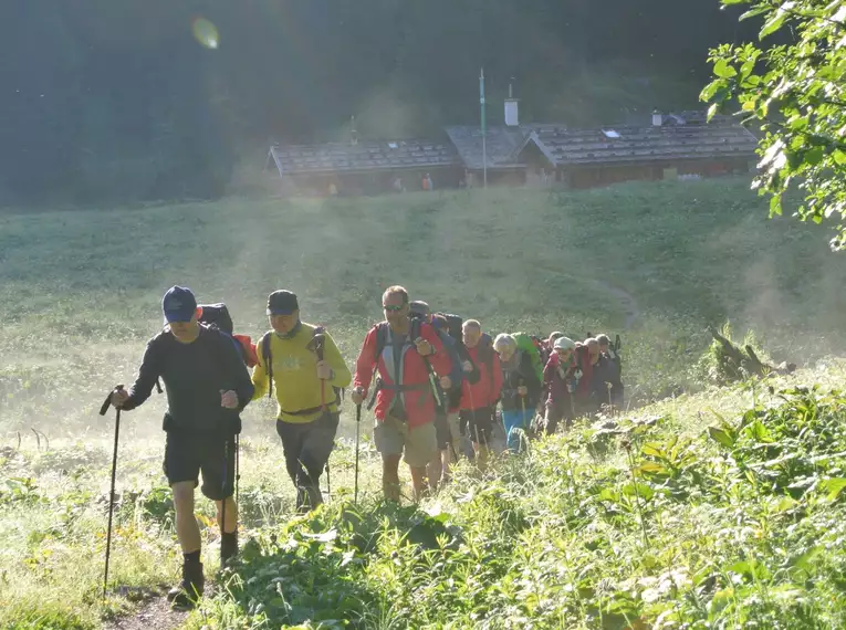 Gruppe von Wanderern auf einem Pfad in grüner alpiner Landschaft