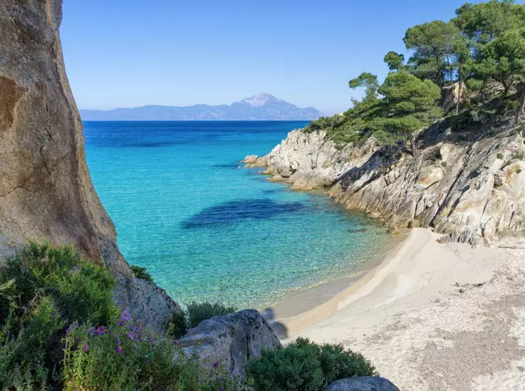 Idyllische Bucht mit türkisblauem Meer, umgeben von Felsen und Pinien in Chalkidiki.