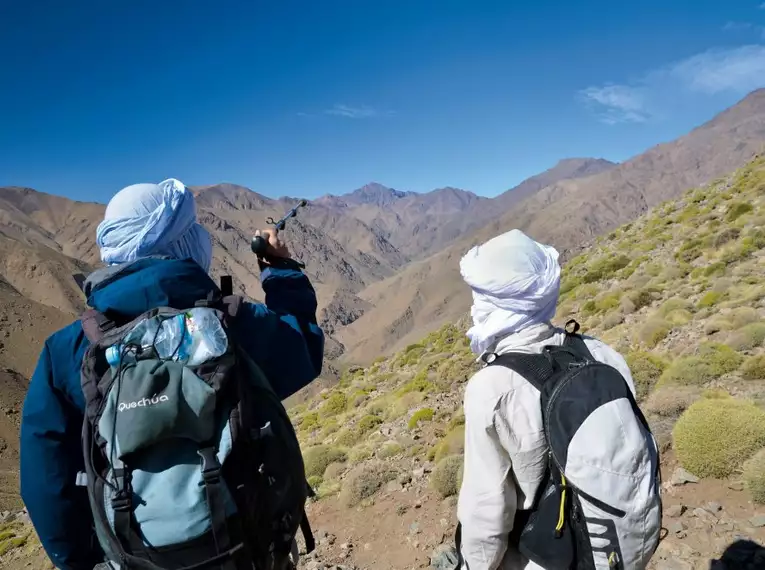 Zwei Wanderer betrachten die Berge des Hohen Atlas in Marokko.