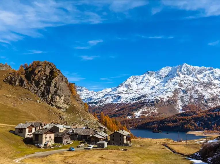 Bergdorf im Engadin mit schneebedeckten Bergen im Hintergrund.