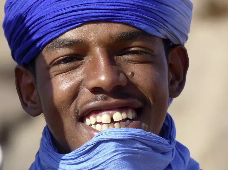 Ein junger Tuareg mit blauem Turban lächelt in die Kamera.