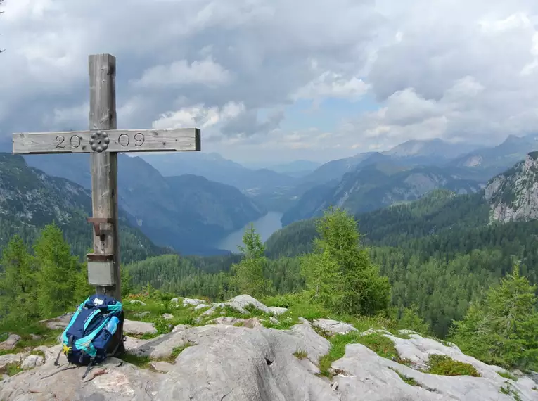 Holzkreuz auf einem Berggipfel mit Blick auf den Königssee und umliegende Berge.