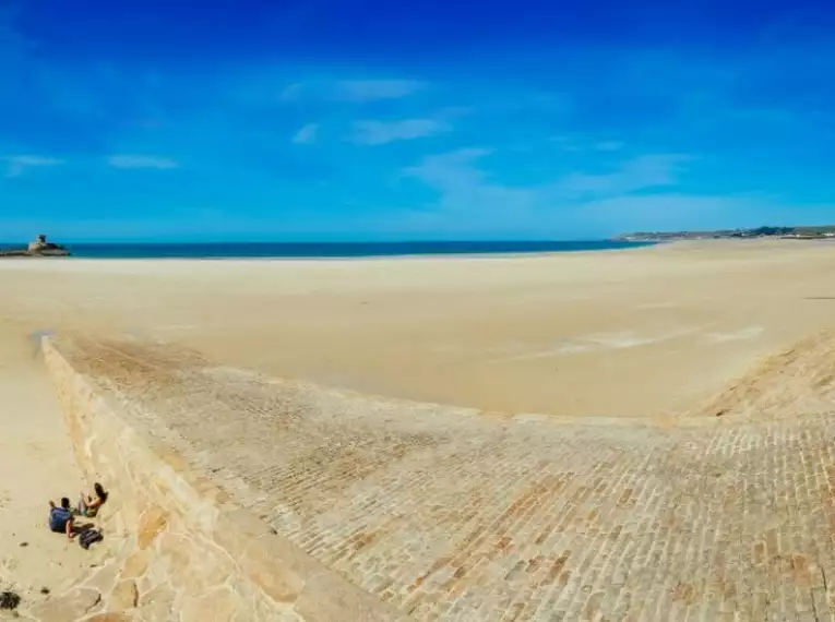 Weißer Sandstrand auf Jersey mit blauem Himmel und weitem Blick über das Meer.