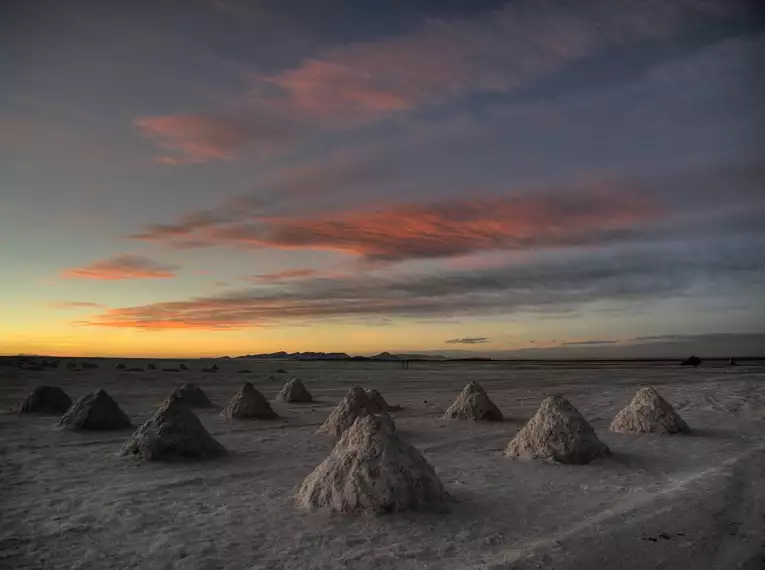 Salzformationen auf dem Salar de Uyuni bei Sonnenuntergang mit beeindruckendem Himmel.