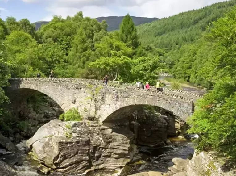 Alte Steinbrücke über einen Fluss in den grünen schottischen Highlands