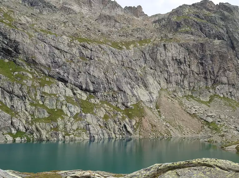 Steiniger Bergsee umgeben von felsigen Alpen, perfekte Kulisse für Wanderungen.