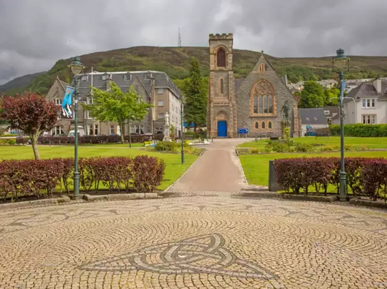 Historische Kirche in einem schottischen Dorf mit Bergen im Hintergrund.